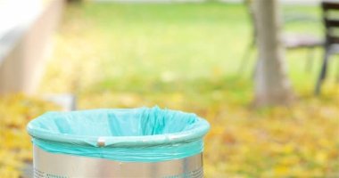 Depo gözü yeşil bir arka plana sahip bir parkta içine çöp atma Kadın el yakın çekim