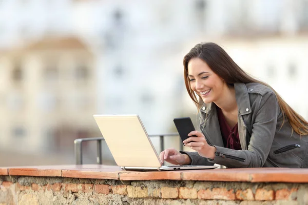 Szczęśliwa Kobieta Korzystająca Smartfona Laptopa Balkonie Miastem Tle — Zdjęcie stockowe