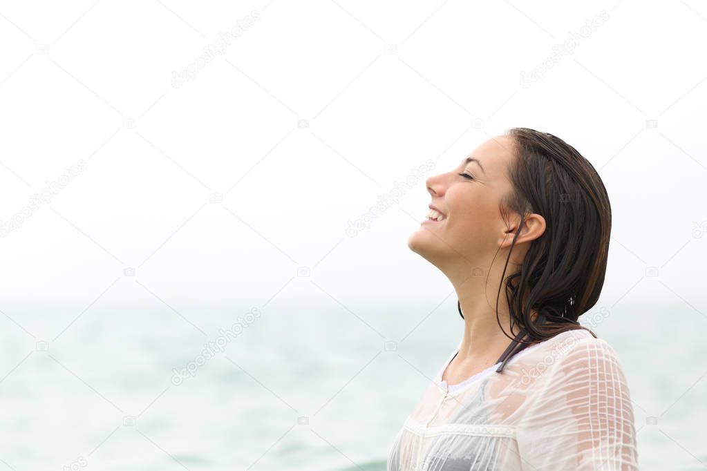 Side view portrait of a wet clothed woman breathing fresh air on the beach