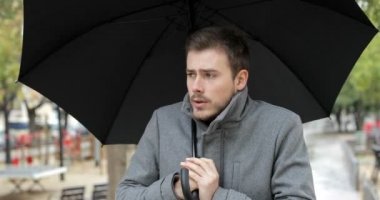 Kameraya bir şemsiye altında doğru bir yağışlı kış günü yürüyüş soğuyor kızgın bir adam portresi önden görünüm
