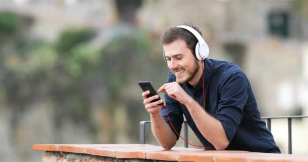 快乐的男人听音乐从智能手机在农村公寓阳台上 并期待离开 — 图库视频影像