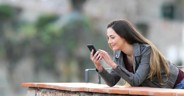 Aufgeregte Frau Checkt Smartphone Inhalte Auf Der Terrasse Einer Ländlichen — Stockvideo