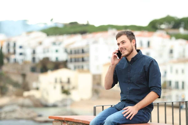Счастливый Человек Разговаривает Смартфону Сидя Выступе Отпуске Прибрежном Городке — стоковое фото