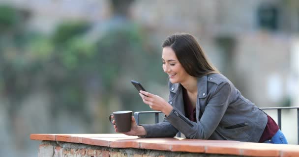 Ευτυχισμένη Γυναίκα Πίνοντας Καφέ Και Χρησιμοποιώντας Ένα Έξυπνο Τηλέφωνο Ένα — Αρχείο Βίντεο