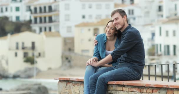バカンス海岸町の棚の上に座って海を考えている観光客の幸せカップル — ストック動画