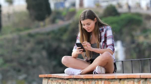 Feliz Adolescente Navegando Por Contenido Del Teléfono Inteligente Sentado Una — Vídeos de Stock
