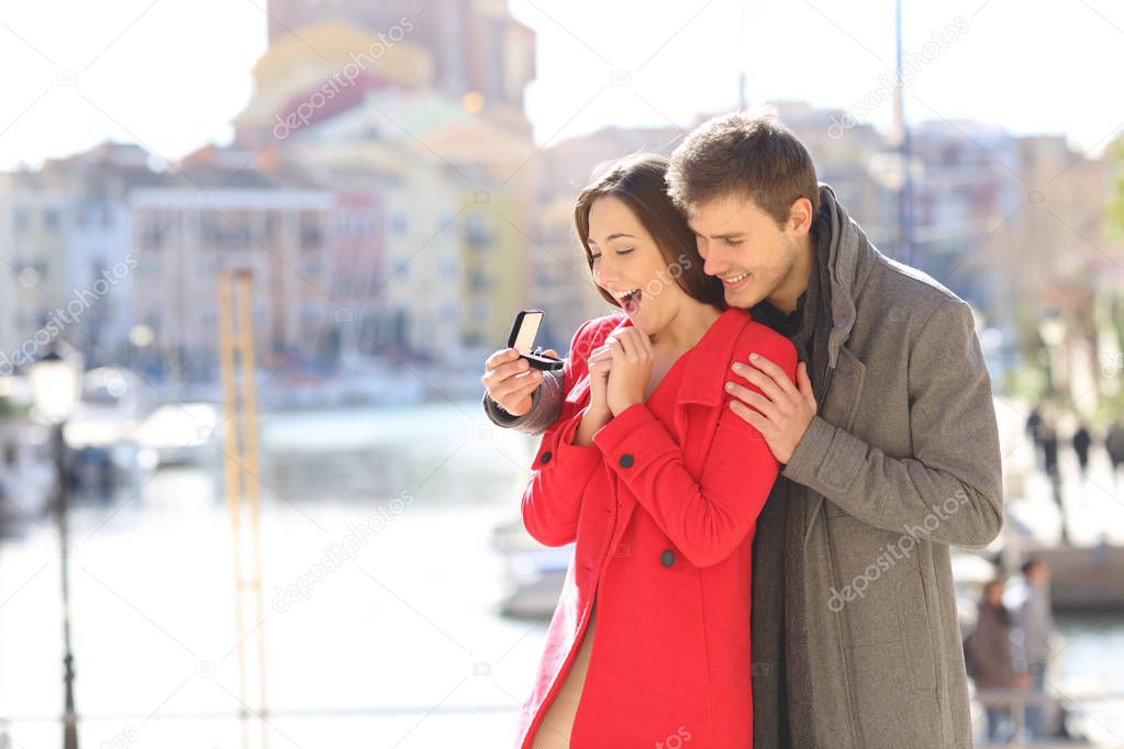 Happy boyfriend asking marry to his glad girlfriend in a coast town in winter