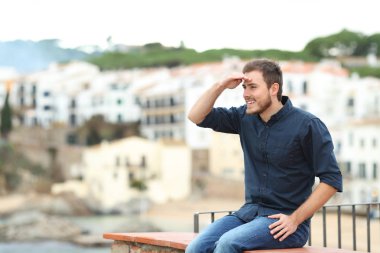 Tatilde bir sahil kasabasında bir çıkıntıda oturan mutlu izci.