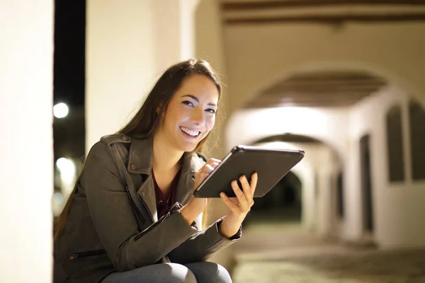 Mulher Feliz Usando Tablet Olhando Para Você Sentado Rua Noite — Fotografia de Stock