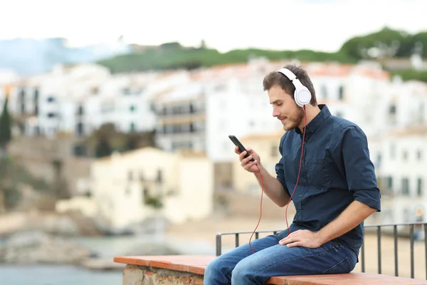 Serious Man Listening Music Smart Phone Sitting Ledge Coast Town — Stock Photo, Image