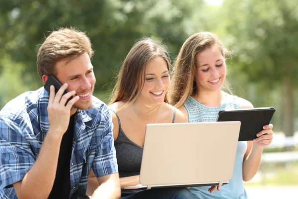 Drei Glückliche Freunde Sitzen Mit Mehreren Geräten Auf Einer Bank — Stockfoto