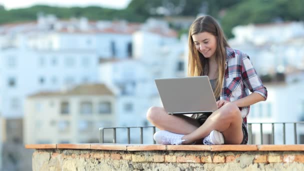 快乐的少女在一个海滨小镇度假时坐在窗台上的笔记本电脑上写字 — 图库视频影像