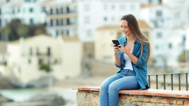 Happy Woman Texting Phone Looks Away Sitting Ledge Vacation — Stock Video