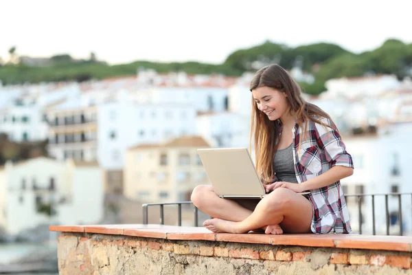 Šťastné teen použití přenosného počítače sedí na římse na město — Stock fotografie