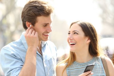 Mutlu romantik çift sokakta buluşarak online müzik paylaşıyor.