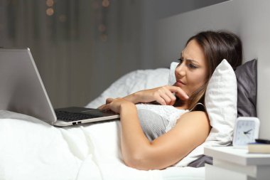 Karışık kadın gece evde yatakta yatıyordu bir dizüstü bilgisayar kullanarak