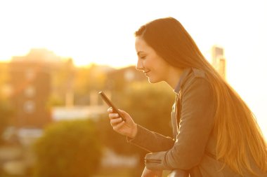 Yan görünümü akıllı telefon içerik sunset kontrol bir balkon rahat bir kadın portresi