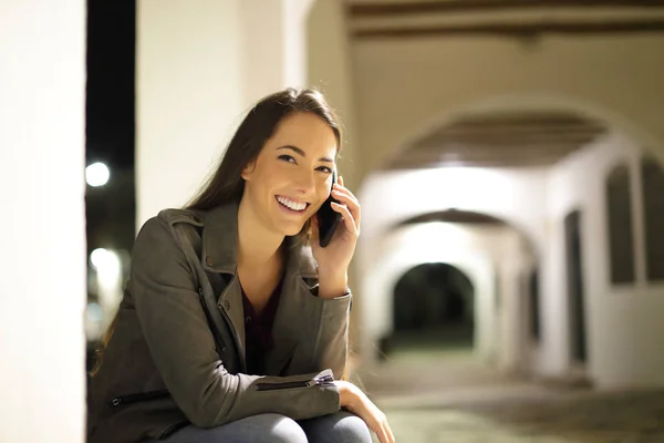 Szczęśliwa Kobieta Rozmawiająca Przez Telefon Patrząca Ciebie Siedzącą Nocą Ulicy — Zdjęcie stockowe