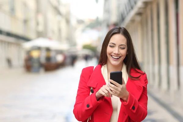 Akıllı Telefon Sokakta Kışın Kullanarak Yürüyüş Kırmızı Mutlu Bir Kadın — Stok fotoğraf