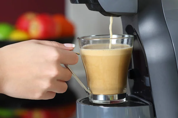 Close up of a woman hand holding a cup in a coffee maker