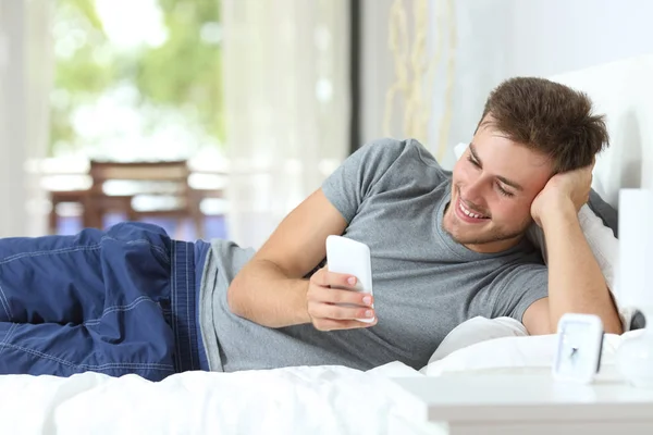 Homem Feliz Verificando Conteúdo Telefone Inteligente Deitado Cama Casa — Fotografia de Stock