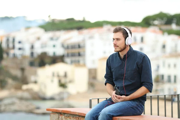 Homme Sérieux Écoutant Musique Téléphone Intelligent Sititng Sur Une Corniche — Photo