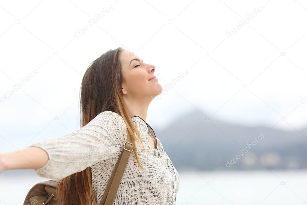 Side view portrait of a happy woman breathing fresh air on the beach or lake