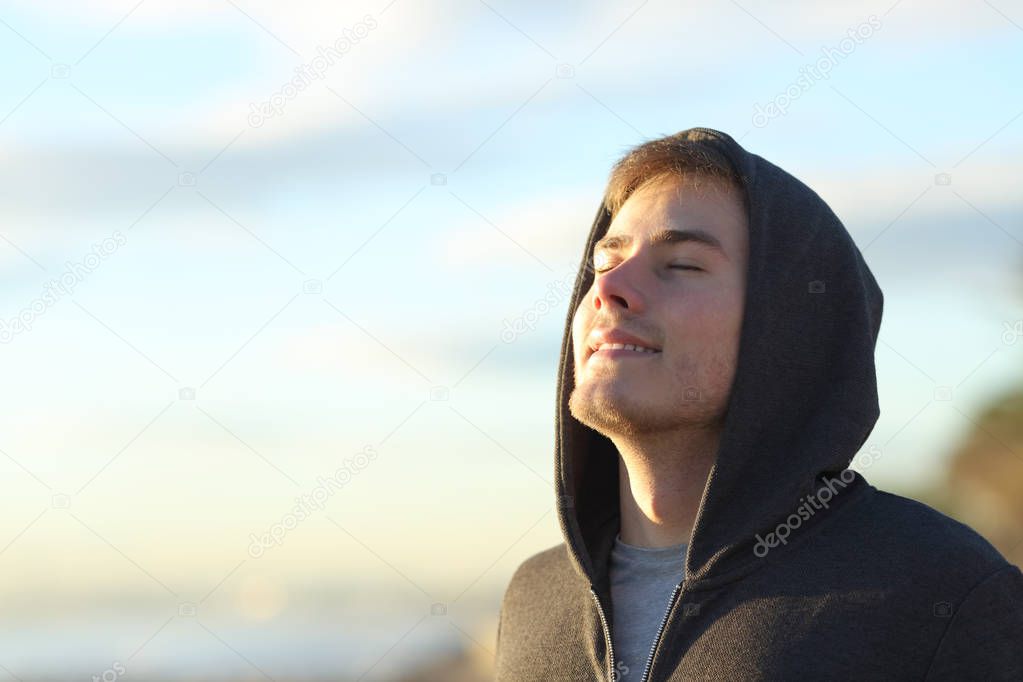 Happy teenage man breathing deep fresh air on the beach