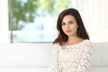 Oturma odasındaki koltukta oturan kendine güvenen bir kadın. 