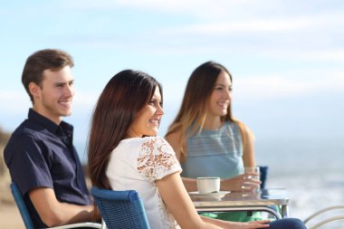 Üç arkadaş bir bar sahilde okyanustan tatil tefekkür