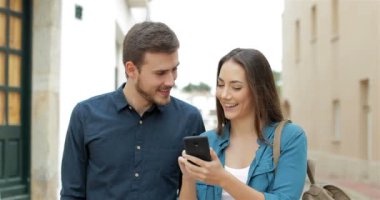Mutlu çift cep telefonu içeriği sokakta tarama kameraya doğru yürüyüş