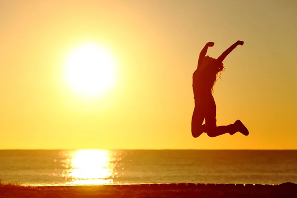 在日落时在海滩上跳跃的一个快乐的女孩的 Baklight — 图库照片