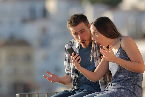 Amazed Couple Checking Smart Phone Content Sitting Ledge Town — Stock Photo, Image