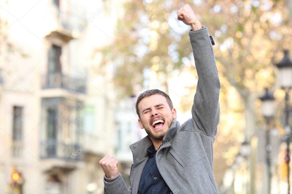 Portrait of an excited man raising arm in the street in winter