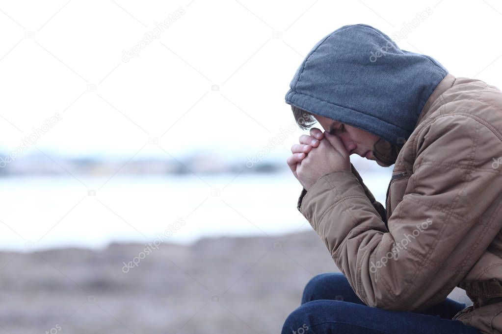 Side view portrait of a sad boy complaining in winter on the beach
