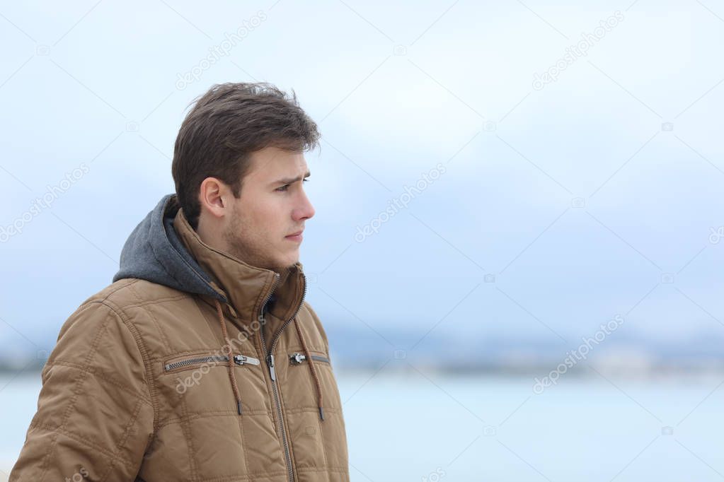 Side view portrait of a sad man looking away on the beach