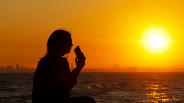 Silueta Una Mujer Hablando Por Teléfono Sentada Banco Atardecer Playa — Vídeo de stock