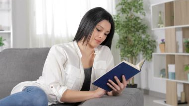 Rahat kadın evde bir kanepede yatan bir kitap okuma