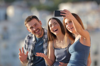 Üç mutlu arkadaş selfies bir akıllı telefon ile açık havada bir kasaba ilçe sınırı günbatımında alarak.