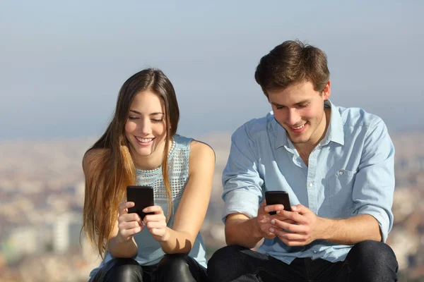Vista Frontal Retrato Casal Feliz Usando Seus Telefones Inteligentes Fora — Fotografia de Stock