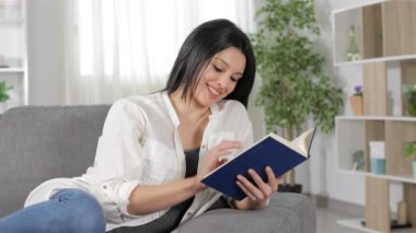 Mutlu kadın evde bir kanepede oturan bir kitap okuma rahatlatıcı