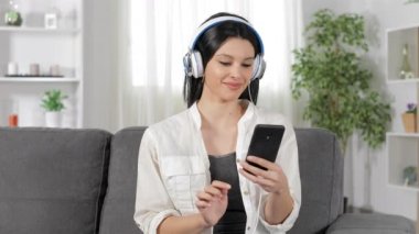 Evde bir kanepede rahatlatıcı müzik dinlerken mutlu bir kadın önden görünümü