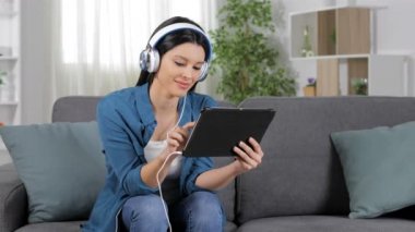 Seçme ve medya içeriği evde bir kanepede oturan tablet izlerken mutlu kadın
