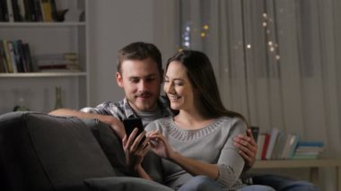 Heyecanlı çift oturma odasında evde bir kanepede oturan inanılmaz akıllı telefon içeriği bulma