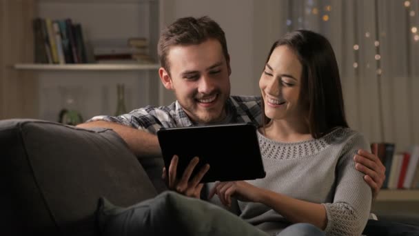 幸福的夫妇在夜间浏览平板电脑内容坐在沙发上在家里 — 图库视频影像