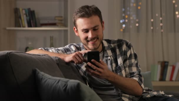 Hombre Feliz Usando Teléfono Inteligente Sentado Sofá Sala Estar Noche — Vídeo de stock