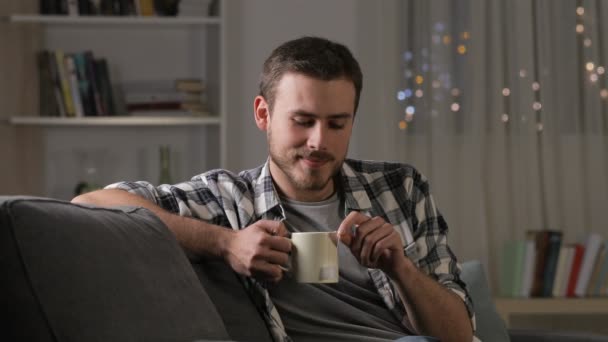 Homem Feliz Bebendo Chá Relaxante Sentado Sofá Sala Estar Noite — Vídeo de Stock