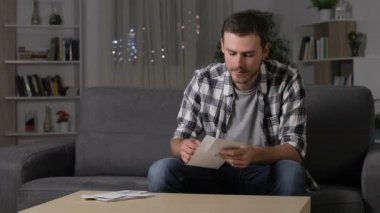 Hayret adam oturma odasında evde bir kanepede oturan bir mektup üzerinde iyi haber okuma
