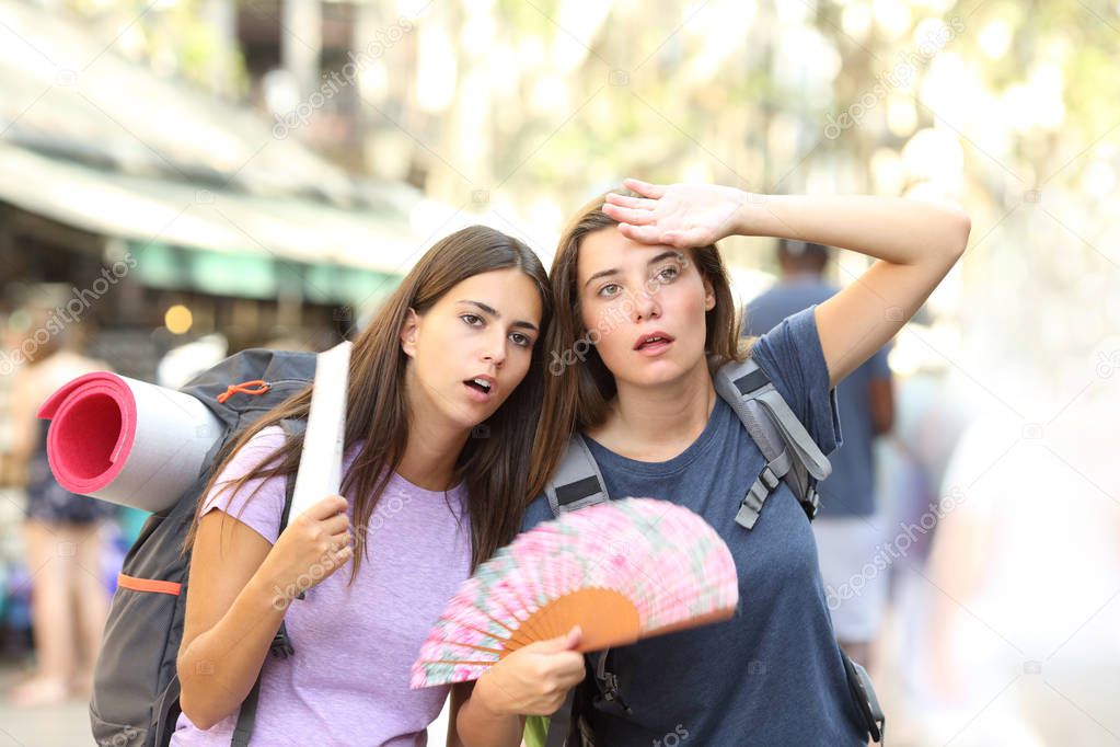 Two backpackers suffering heat stroke walking on the street and fanning on summer vacation