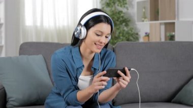 Mutlu kadın akıllı telefon oturma odasında evde bir kanepede oturan video izleme